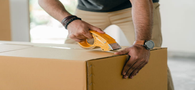 Detalle de manos embalando una caja